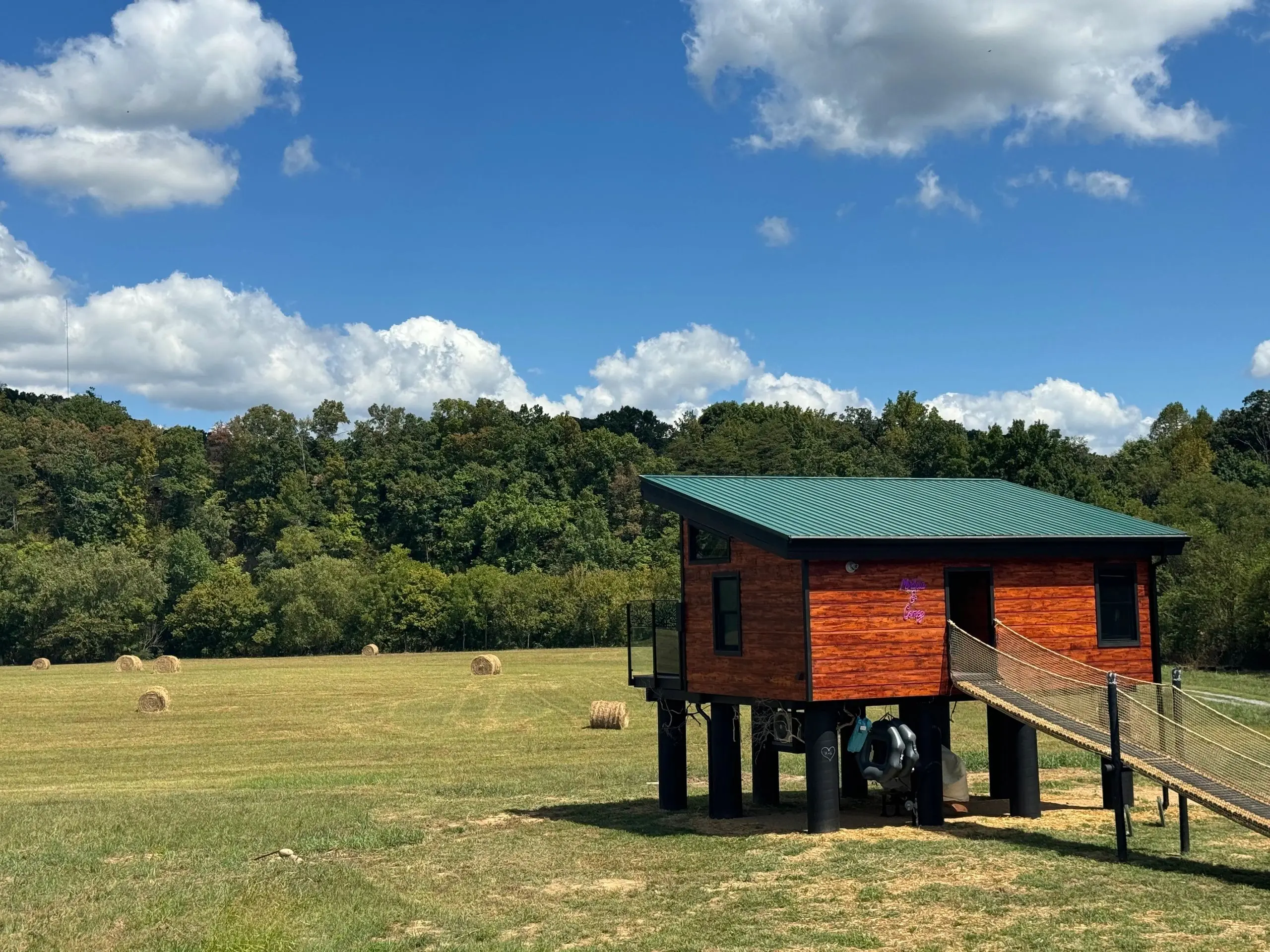 Elevated cabin in a sunny rural field.