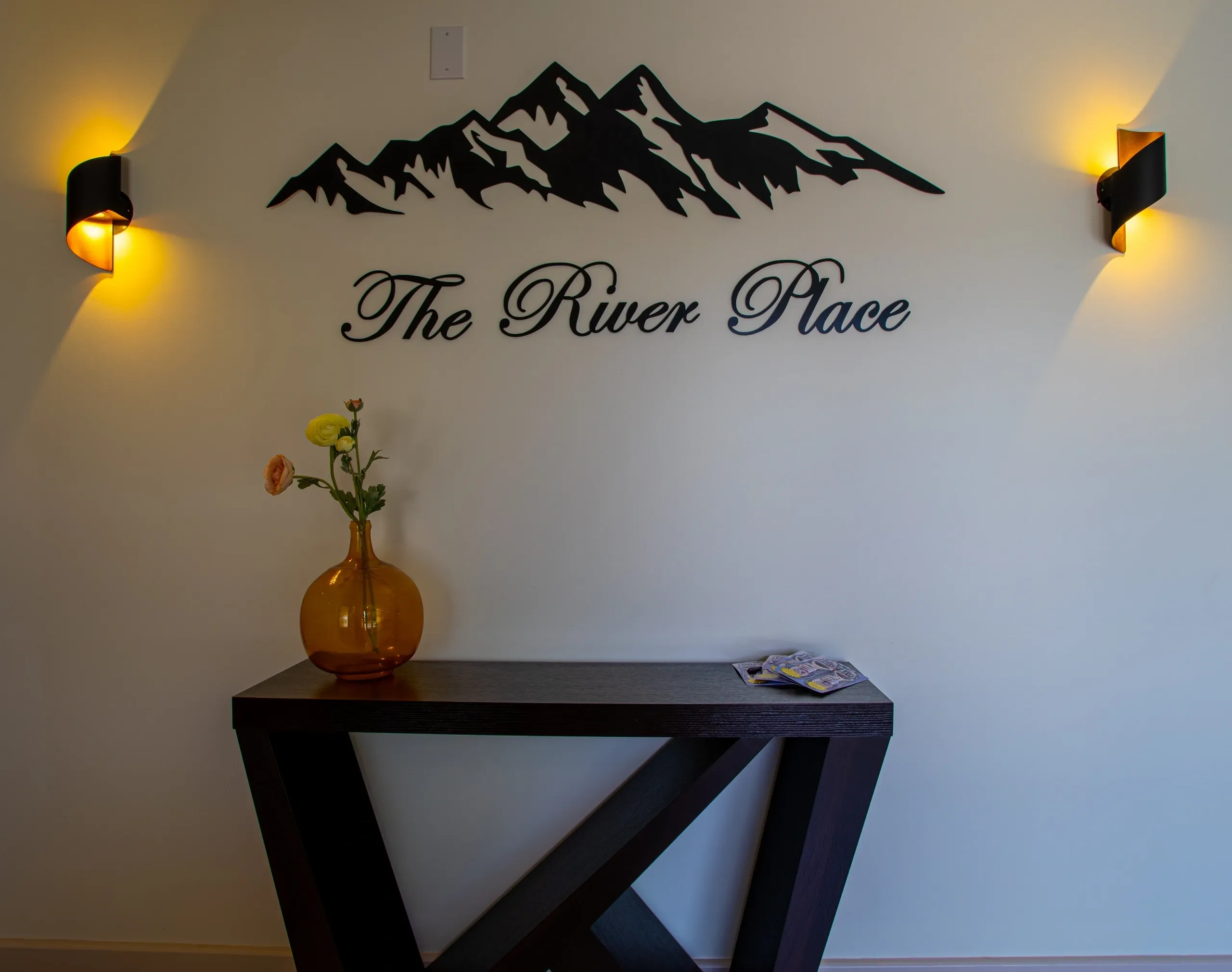 Mountain decor above console table with vase.