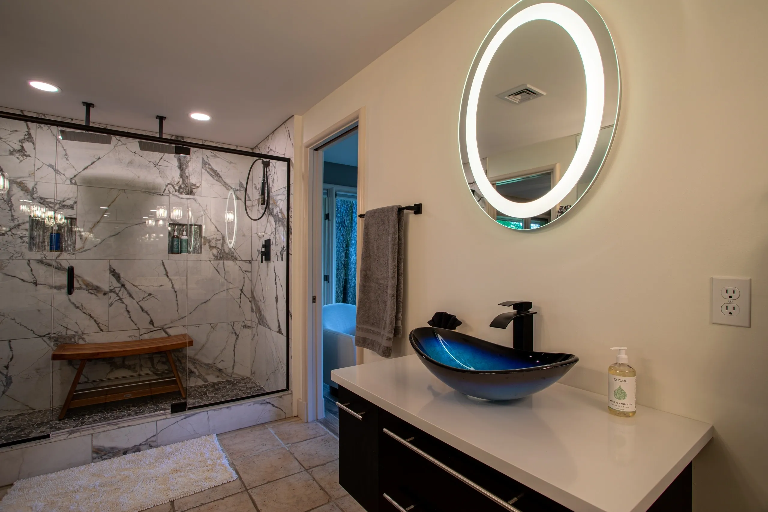 Modern bathroom with glass shower and illuminated mirror.