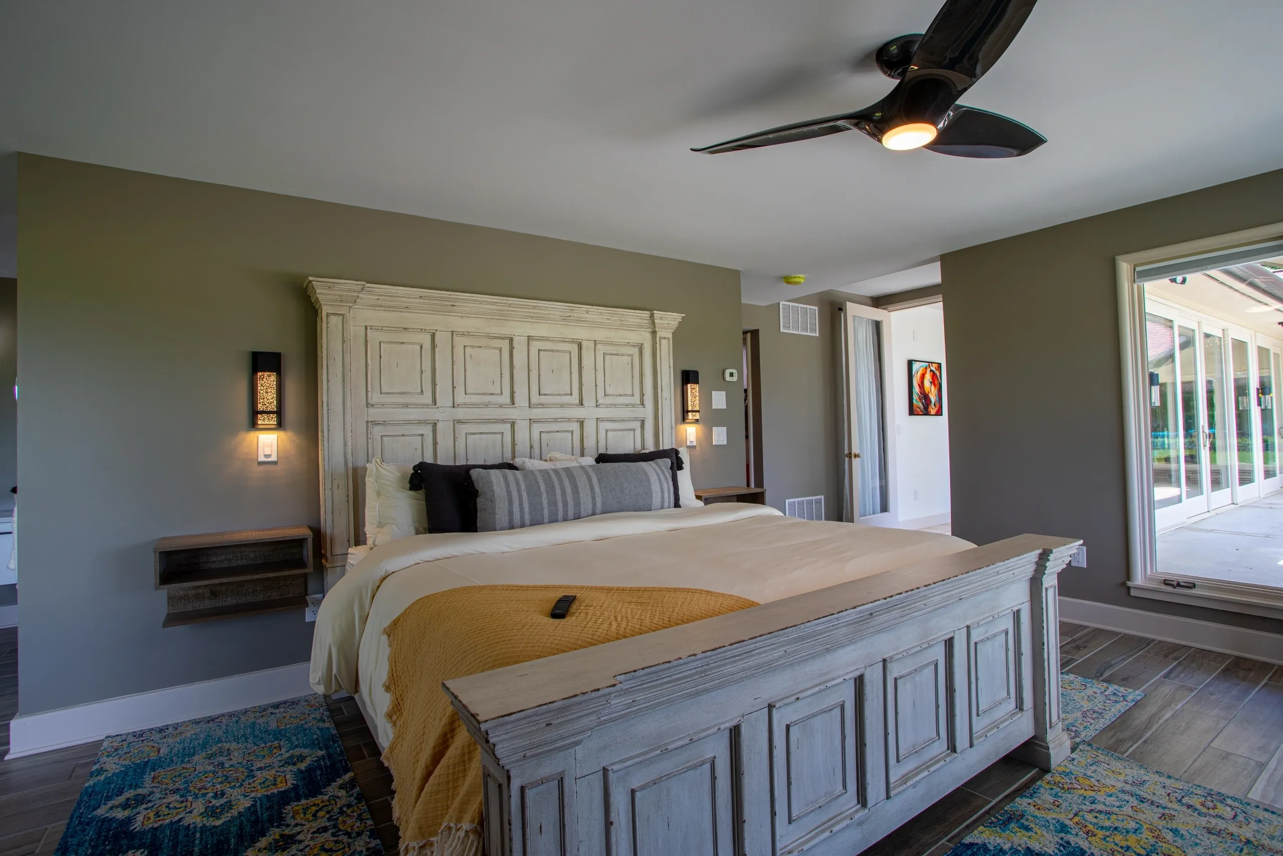 Spacious bedroom with wooden bed and fan.