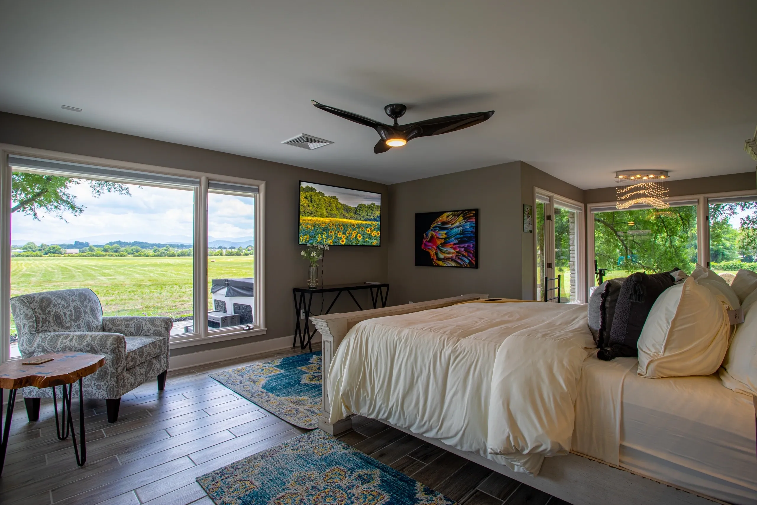 Modern bedroom with large windows and artwork.