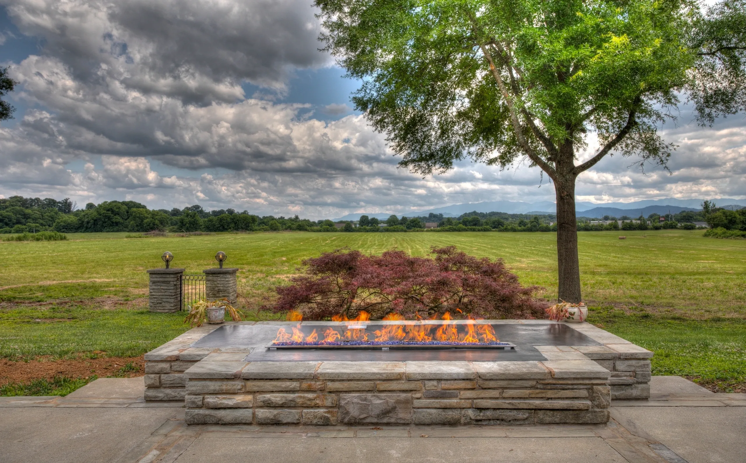 Outdoor fire pit with scenic countryside view.