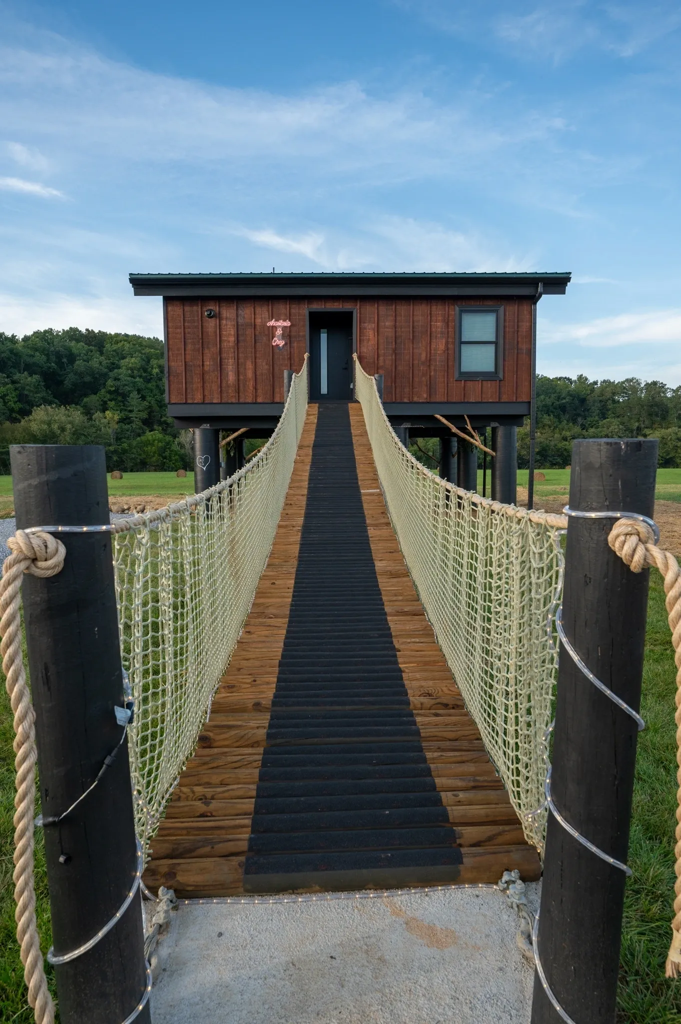 Elevated cabin with rope bridge entrance.