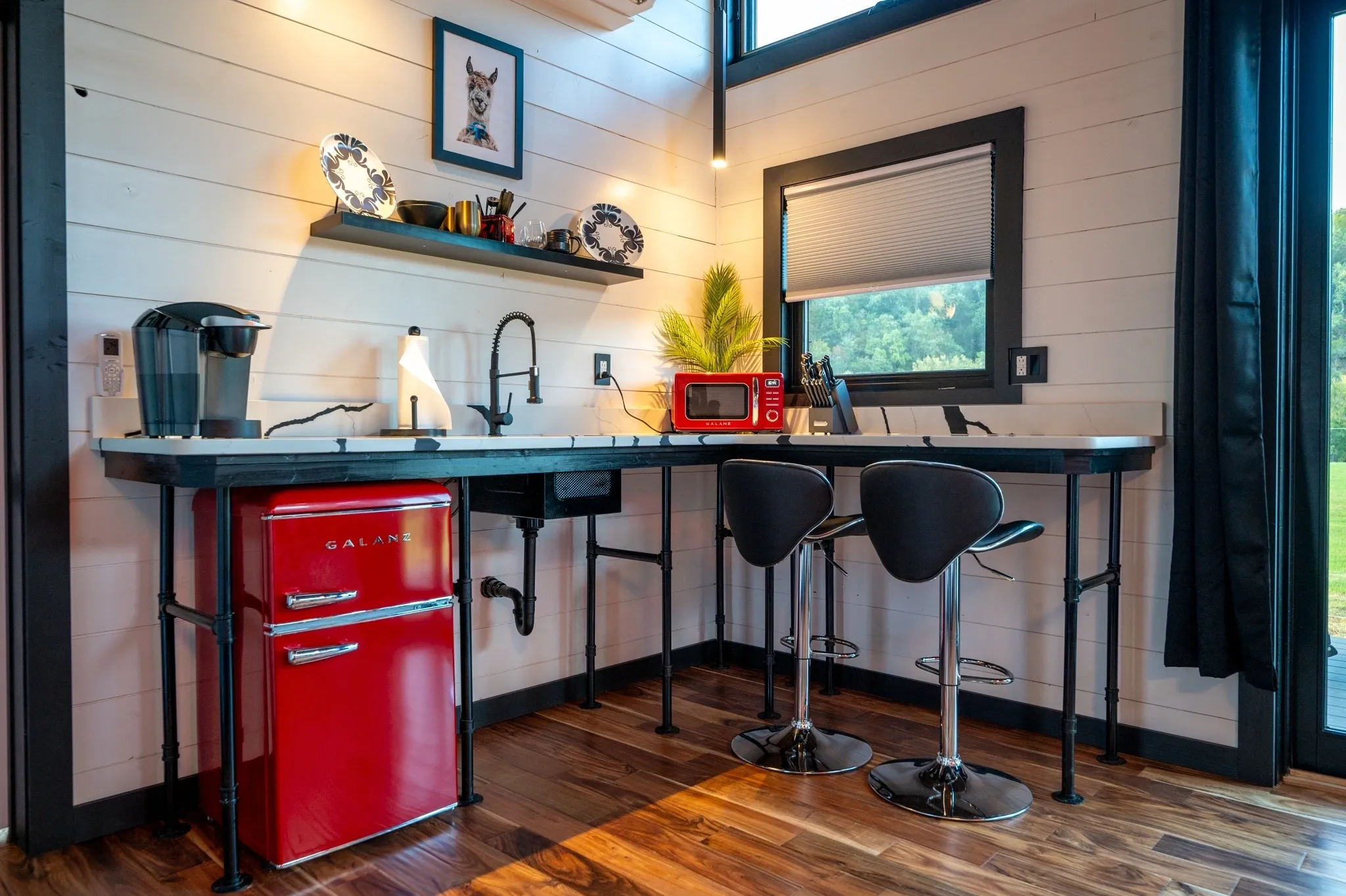 Modern kitchen with red appliances and chairs.