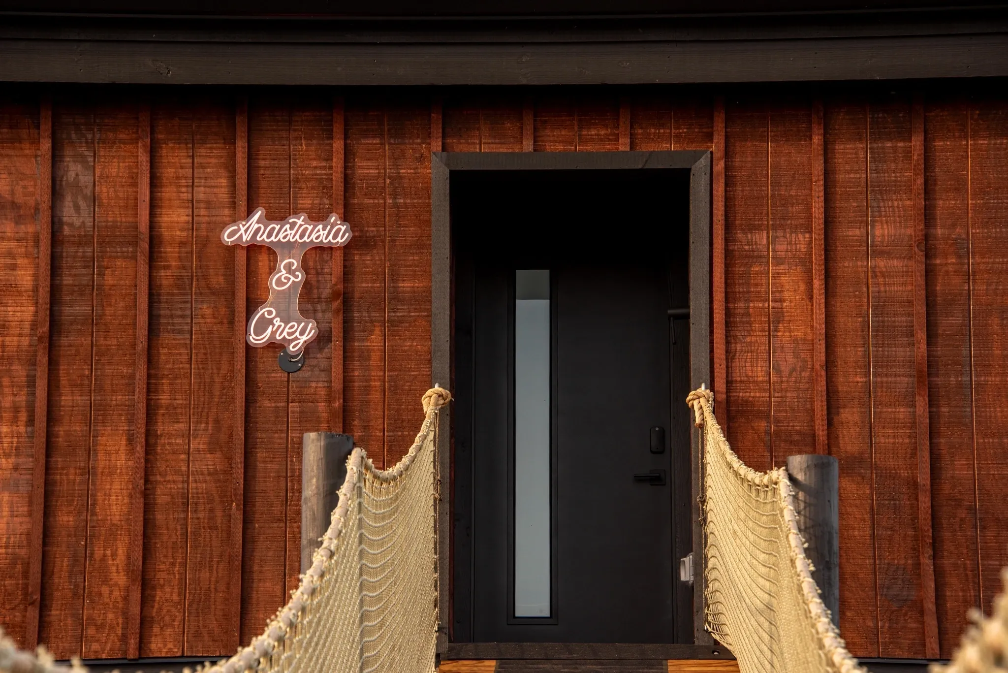 Wooden entrance with rope bridge and sign.