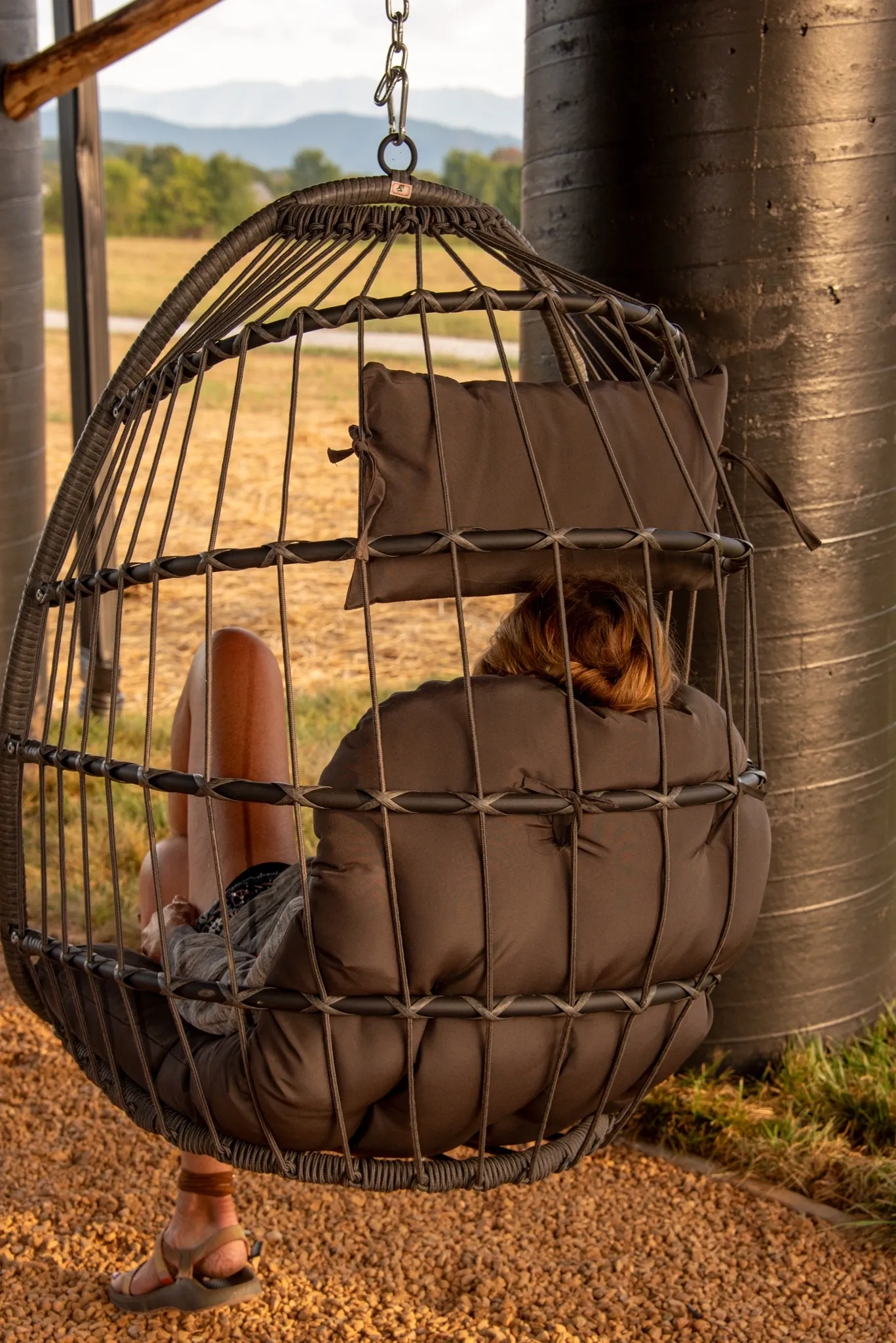 Person relaxing in outdoor hanging chair.