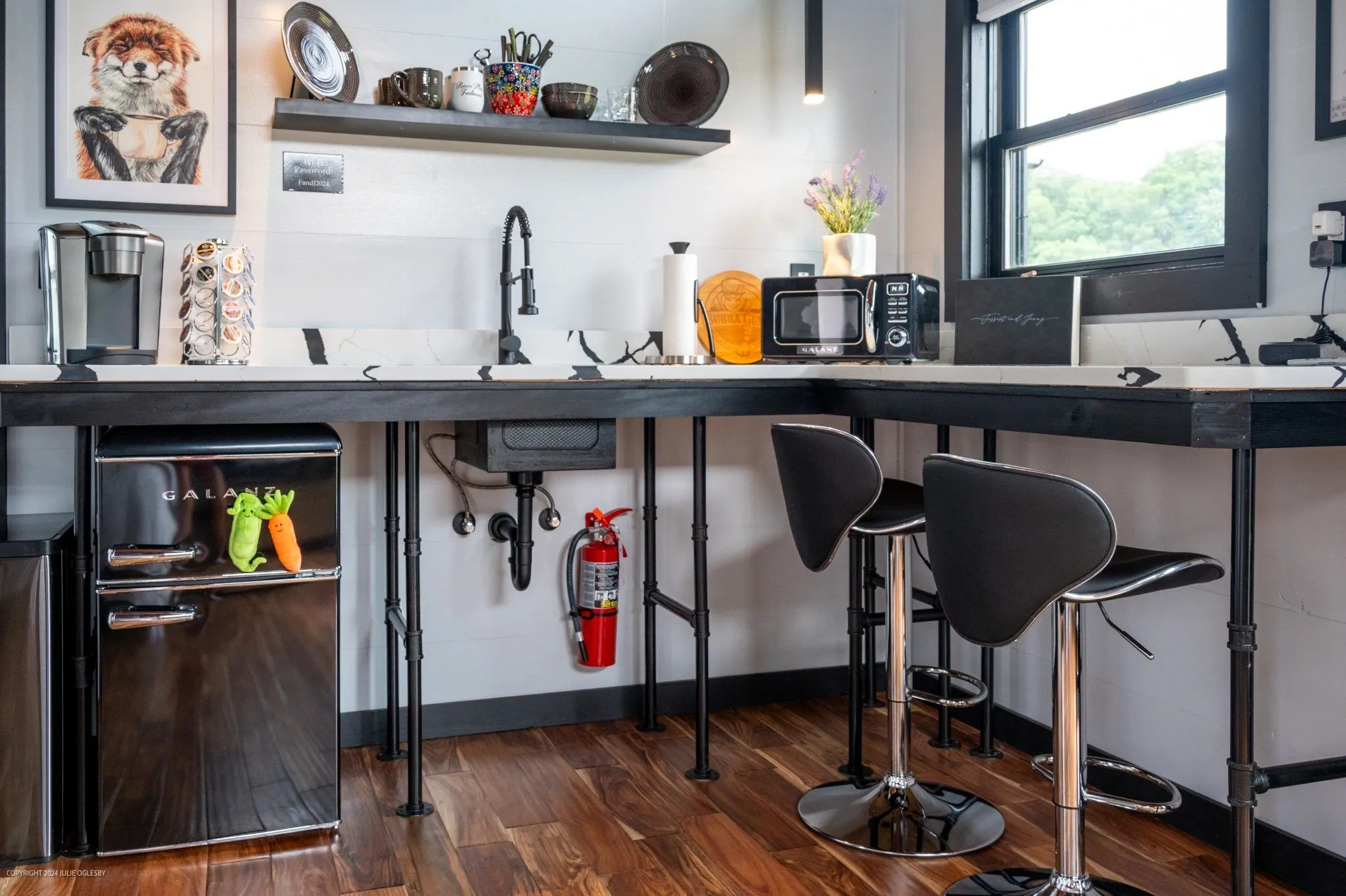 Modern kitchenette with stools and appliances.