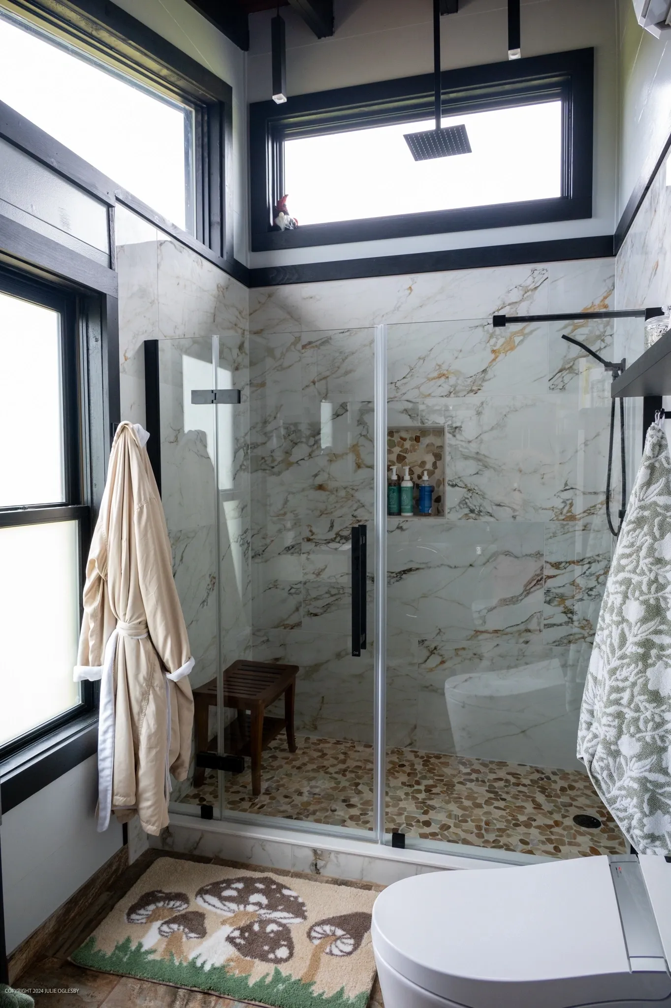 Modern bathroom with marble shower and windows.