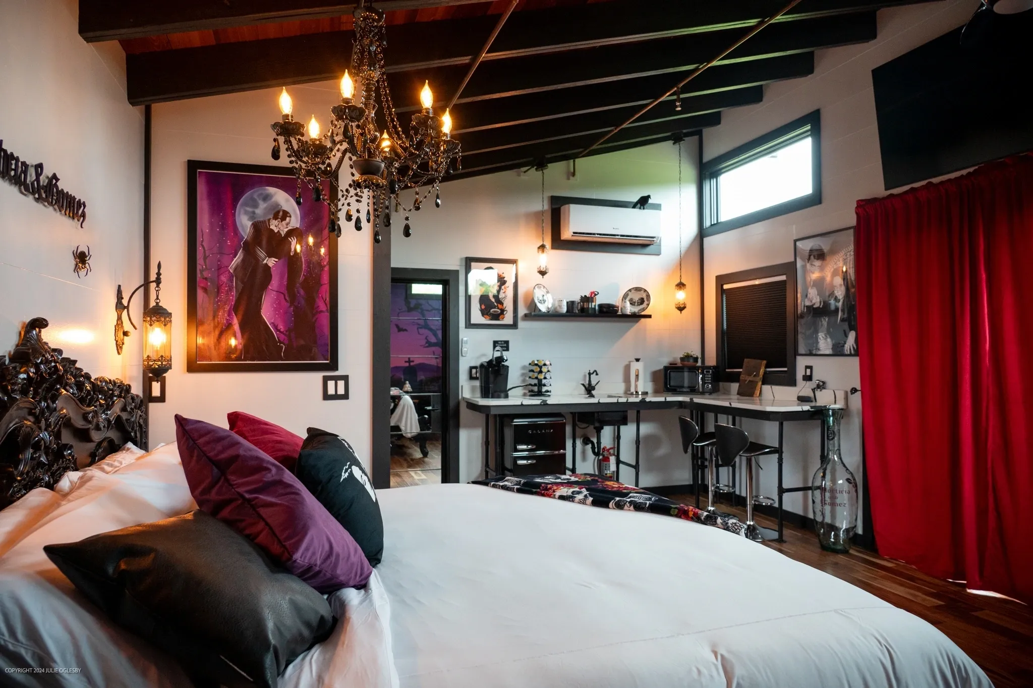 Gothic bedroom with chandelier and wall art.