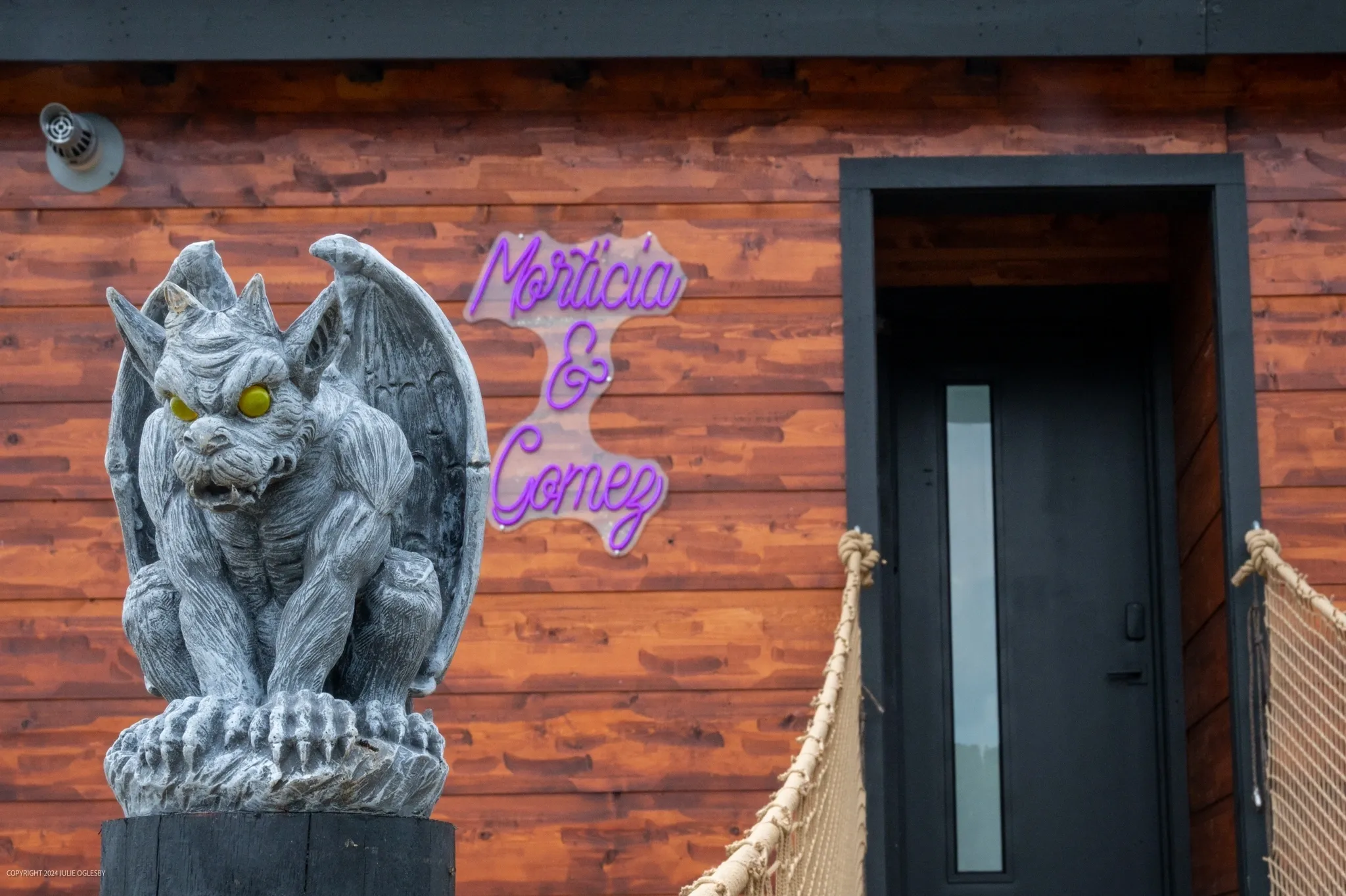 Gargoyle statue outside wooden building entrance.