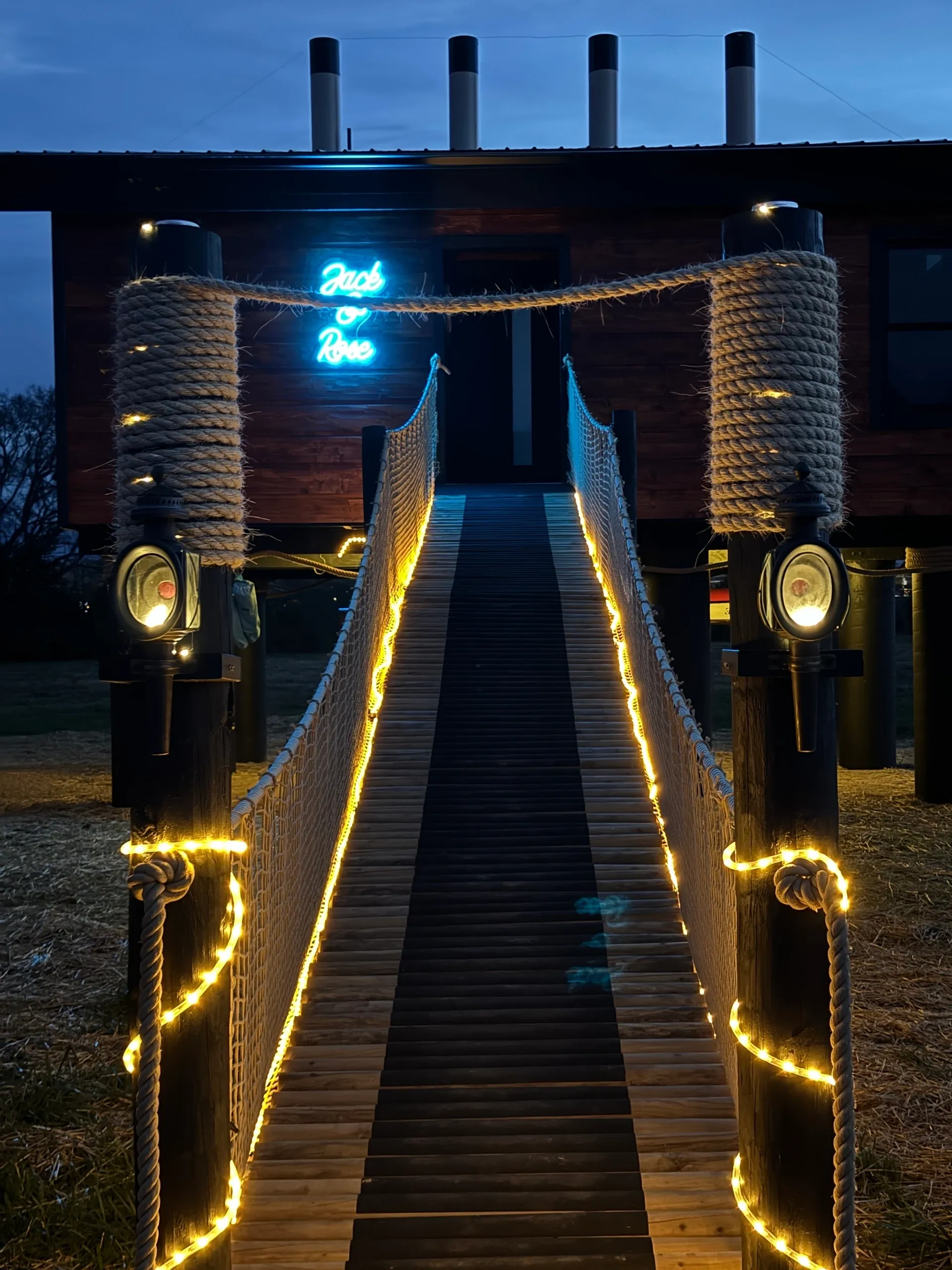 Illuminated bridge leading to building entrance.