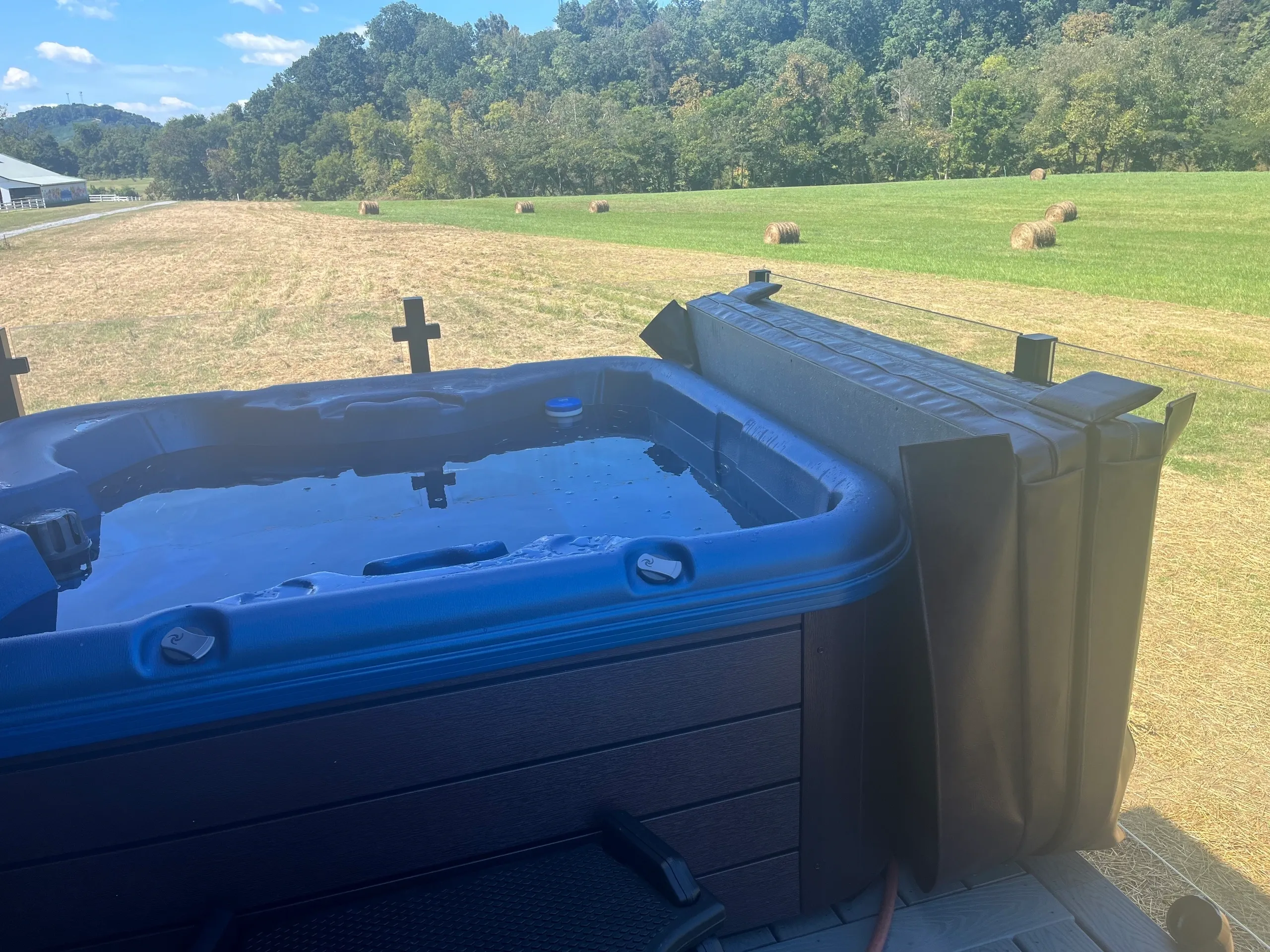 Hot tub overlooking a scenic grassy field.