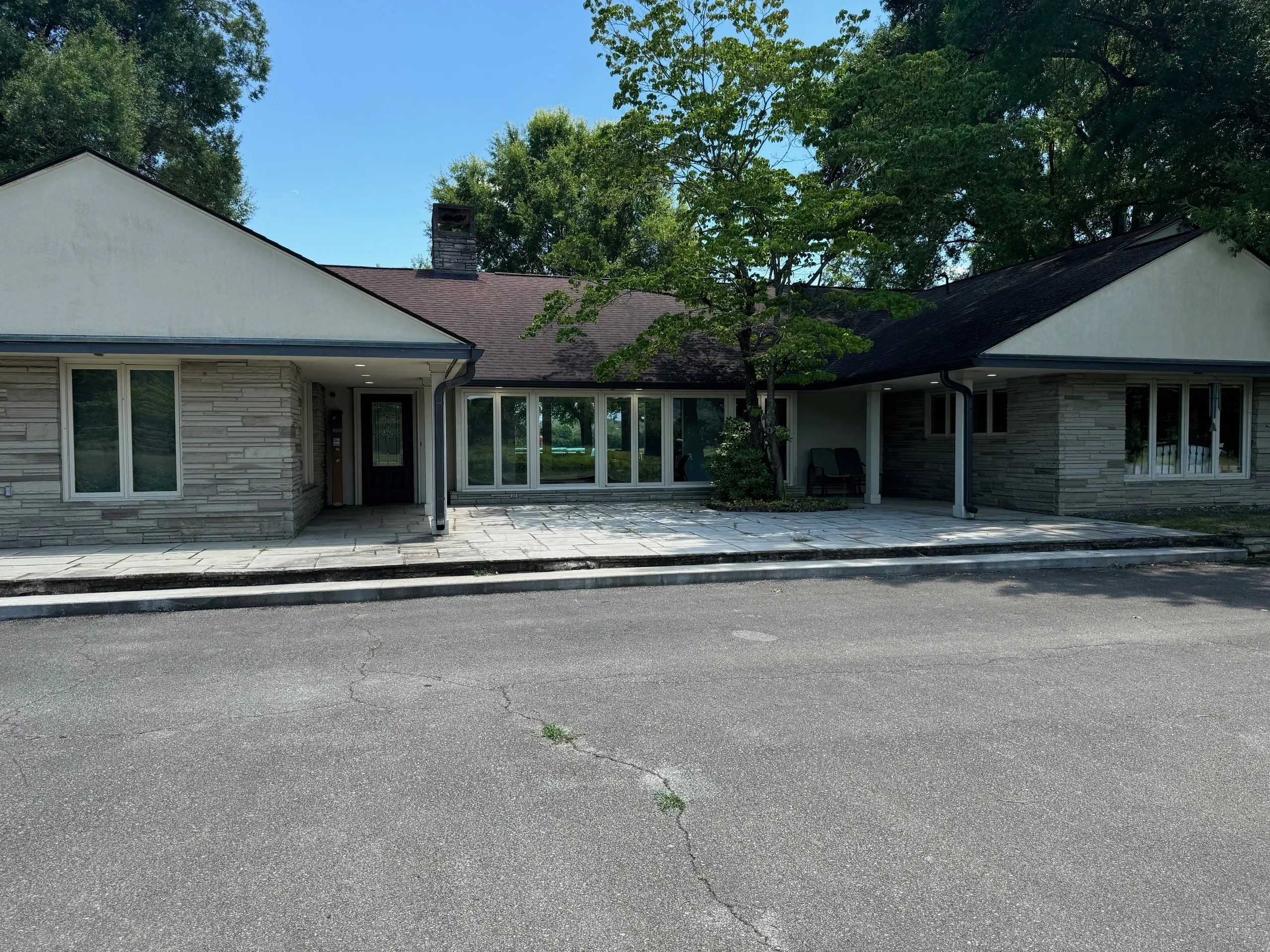 Single-story building with large windows, trees.